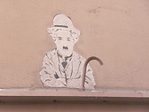 Charlie Chaplin sur un mur, qui picote du pain dur...